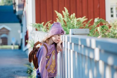 Portrait of a young girl leaning on a fence waiting for school