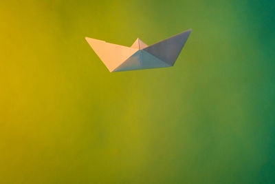 Close-up of paper boat with smoke against green background