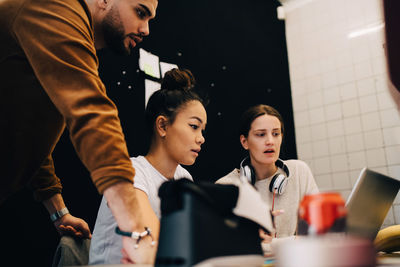 Multi-ethnic hackers discussing over laptop at small creative office