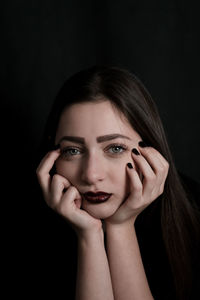 Close-up portrait of sad young woman against black background