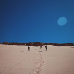 People standing on sand with sky in background
