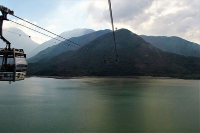 Overhead cable car over lake against mountains