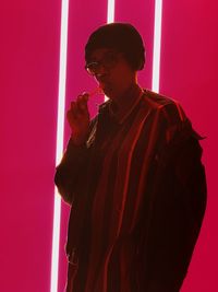 Young man standing against red wall