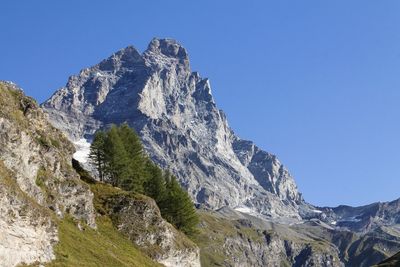 Low angle view of snowcapped mountains against clear blue sky