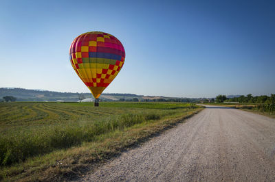 Hot air balloon flying over road against sky