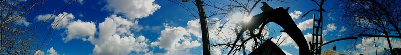 Low angle view of bare trees against cloudy sky