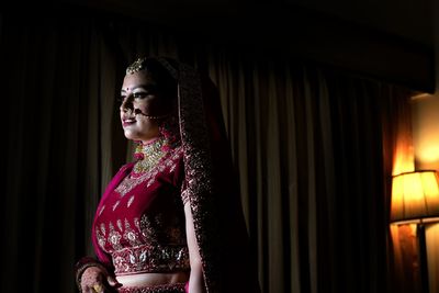 Young woman standing against curtain