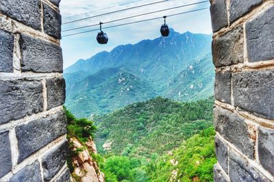 Low angle view of overhead cable car against mountains