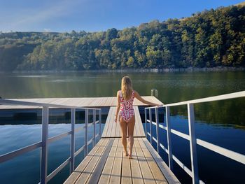 Rear view of woman standing by lake
