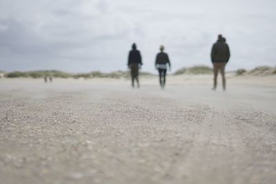 Rear view of people walking on landscape against sky