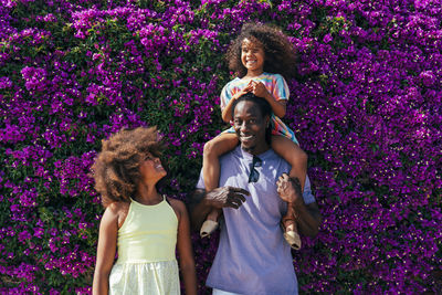 Smiling girl looking at father carrying daughter on sister