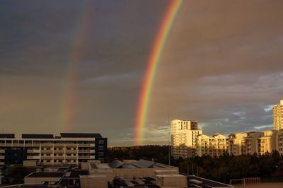 Rainbow over buildings in city against sky