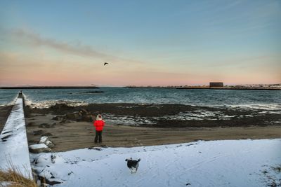 Man standing on beach against sky during sunset