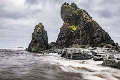 Rock formation by sea against sky