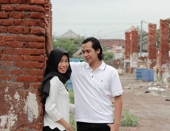 Young couple standing against wall