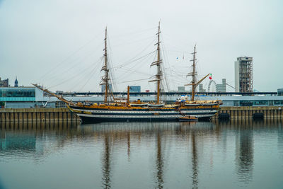 Boats moored at harbor against clear sky