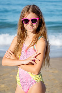 Fashion cute young girl posing on the beach in a summer swimsuit. 