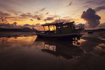 Boat moored on sea against sky during sunset