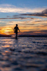 Silhouette man standing on beach against sky during sunset