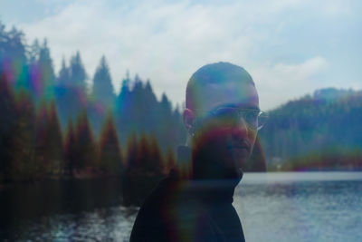 Portrait of man standing against lake and sky