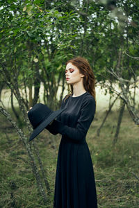 Young woman standing against trees