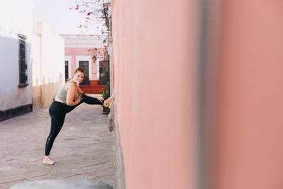 Full length of woman stretching on wall