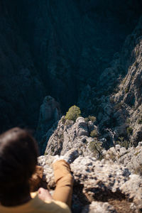 Rear view of woman sitting on rock