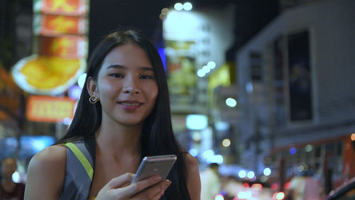 Portrait of young woman using mobile phone at night