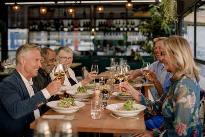 Happy senior male and female friends toasting wineglasses in restaurant