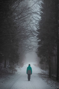 Young girl in a green winter jacket walks in the ugly, foggy and cold weather in beskydy moutains