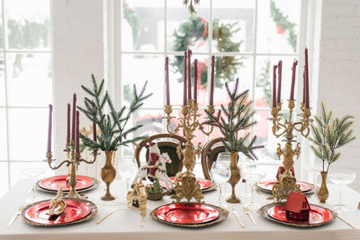 Christmas serving of a festive new year's dinner. candles in candlesticks, spruce branches, red 