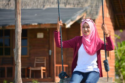 Portrait of young woman swinging on sunny day