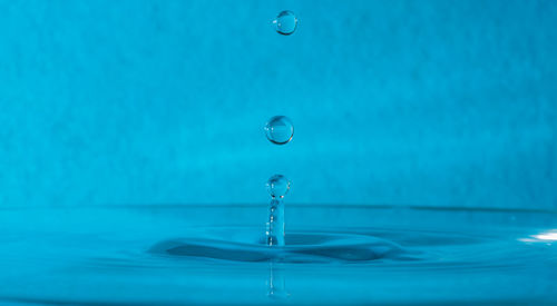 Close-up of drop falling in blue water