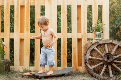 Full length of shirtless boy standing against wall