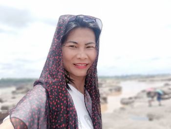 Portrait of smiling young woman standing on beach