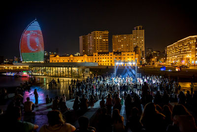 Crowd at illuminated city against sky at night