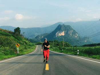 Full length of woman running on road against landscape