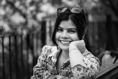 Black and white portrait of a pretty indian woman with sunglasses on head smiling at camera