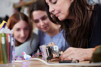 Young colleagues looking at mature technician making model in workshop