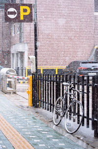 Bicycle parked on snow covered wall