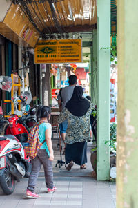 Rear view of people walking on street in city