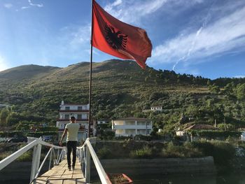 Rear view of man flag on mountain against sky