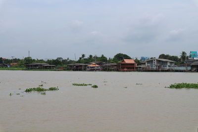 Scenic view of river by buildings against sky