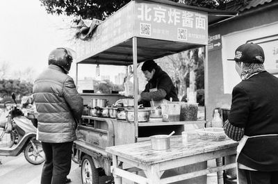 Rear view of people standing at market stall