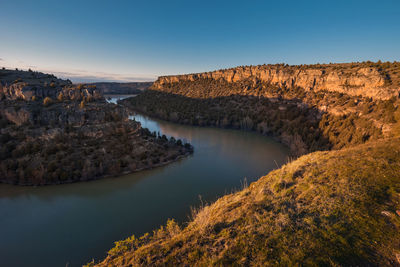 Scenic view of river amidst landscape against blue sky