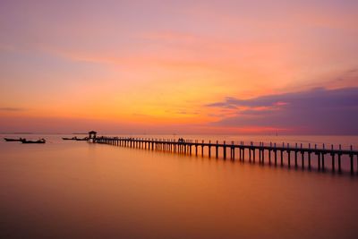 Pier on sea against sky during sunset