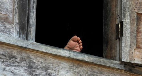 Close-up of person soles of the feet on window of house