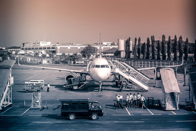 Airplane on airport runway against sky in city