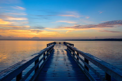Pier amidst sea during sunset