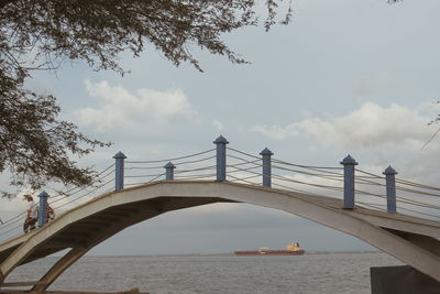 Bridge over river in city against sky